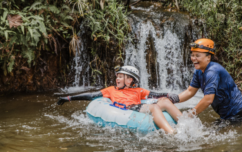 Two friends tubing near a small waterfall