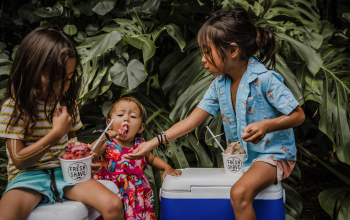 Two young girls and a toddler enjoying shaved ice.