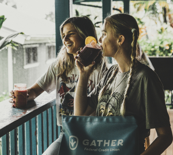 Two young women drinking smoothies on porch