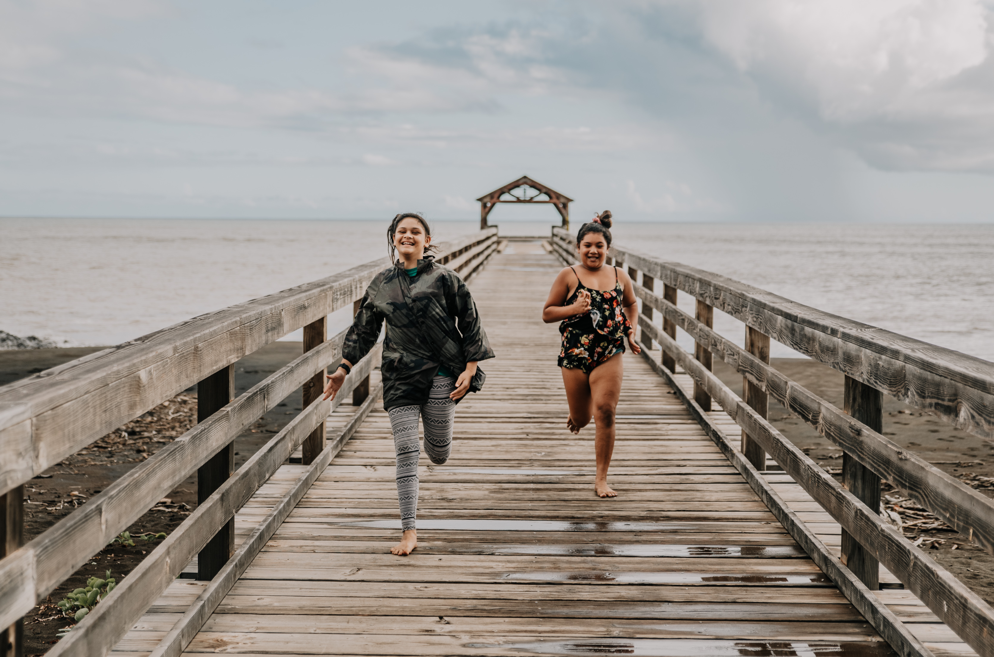 two girls running on a wooden bridge
