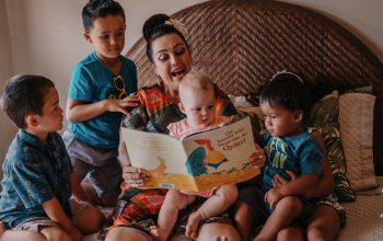 A woman reading a story to 4 children.