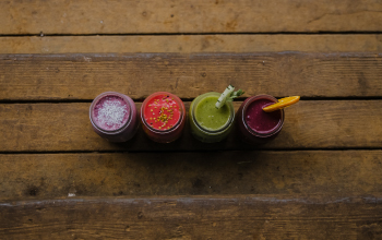 Four smoothies lined up in a row on a porch